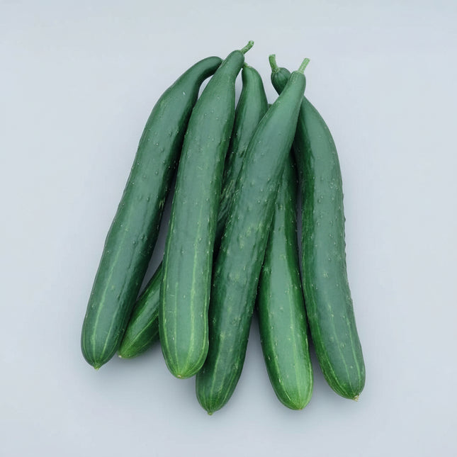 Several long, dark green cucumbers resting in a woven basket among green leaves and small yellow flowers.