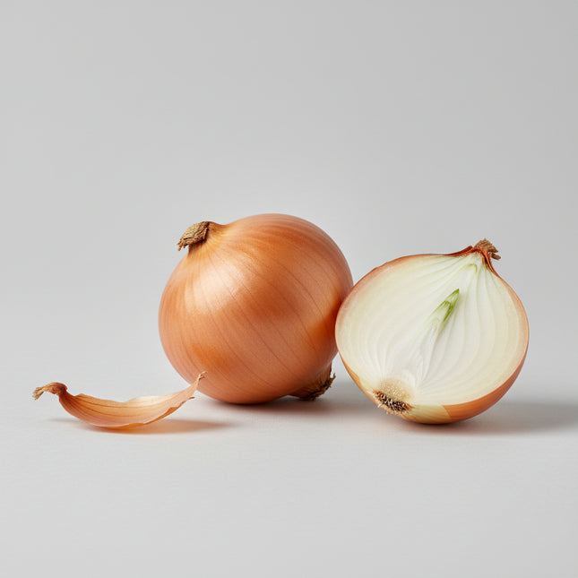 Fresh yellow onions with one onion cut in half to show the layered white interior, resting on a wooden surface with a blurred green background.